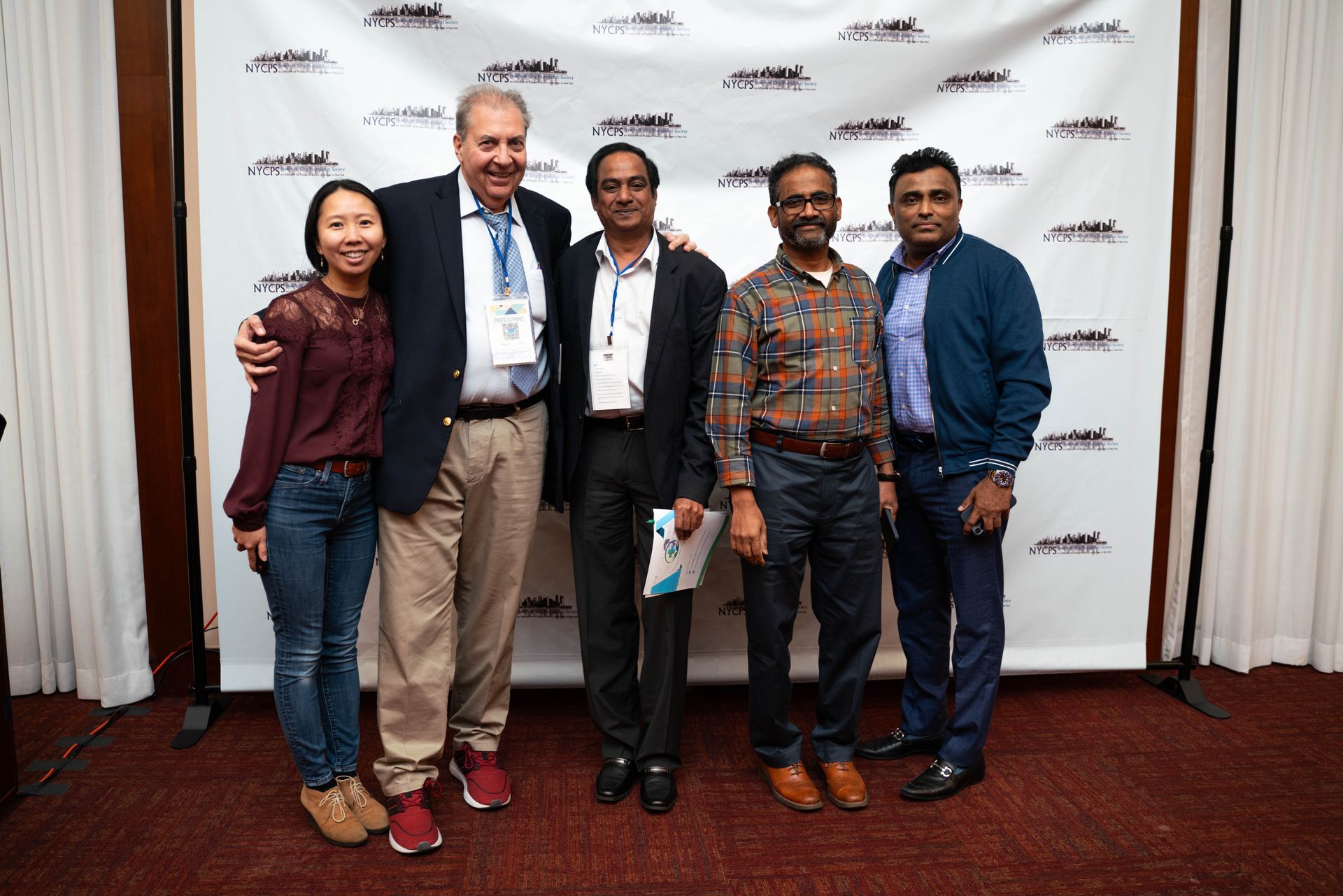 Group photo of attendees in front of the photo wall
