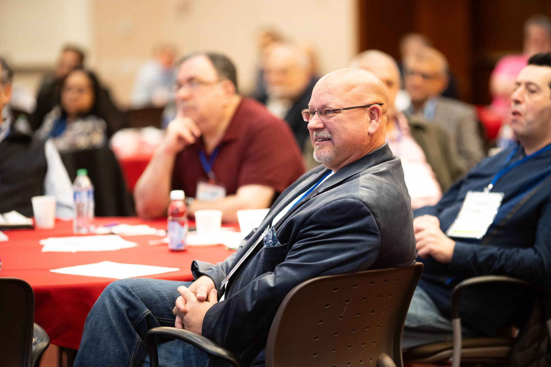 Attendees seated at round tables listening to a presentation