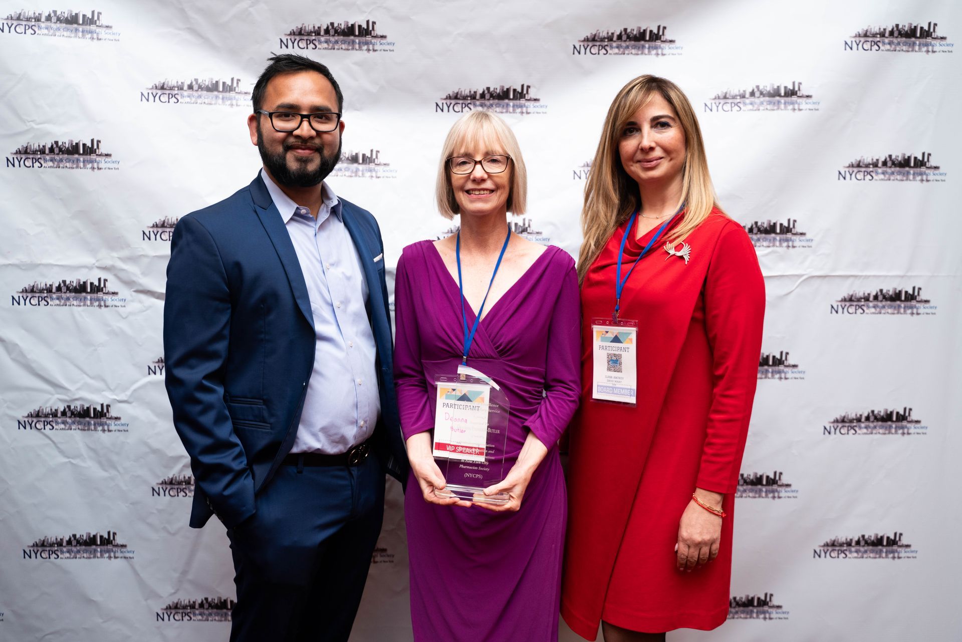 Three guests holding awards in front of the photo wall